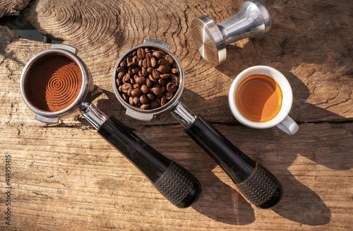 A portafilter with coffee beans, a tamper portafilter with ground coffee, an espresso shot black table.