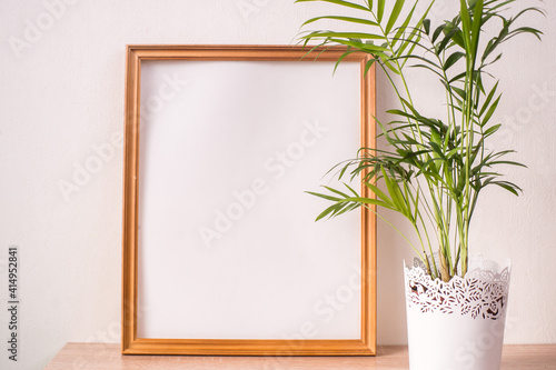 Portrait broun picture frame mockup on wooden table. White wall background. Scandinavian interior. 