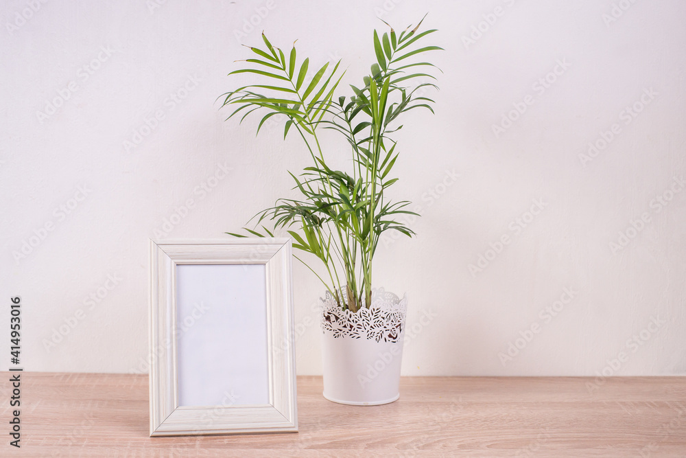 Fototapeta premium Portrait white picture frame mockup on wooden table. White wall background. Scandinavian interior. 
