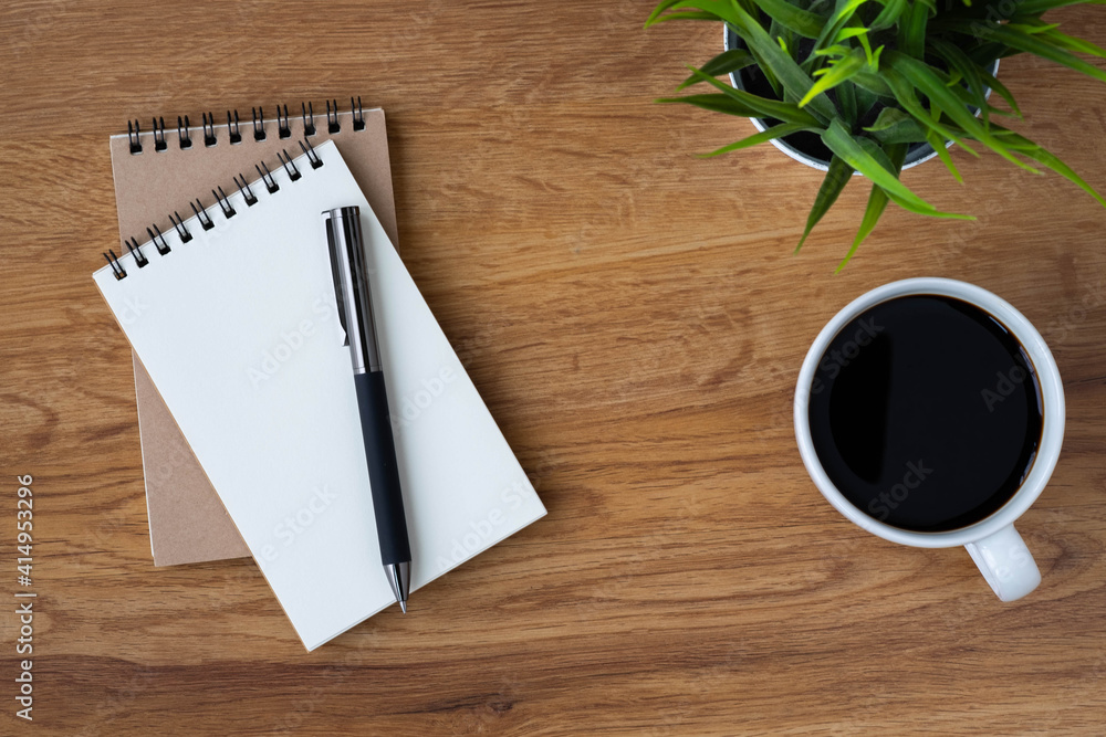 Top view of open school notebook with blank pages, coffee cup and pen for taking write notes on table background. Flat lay, creative workspace office. Business-education concept with copy space. Top view of open school notebook with blank pages, coffee cup and pen for taking write notes on table background. Flat lay, creative workspace office. Business-education concept with copy space.