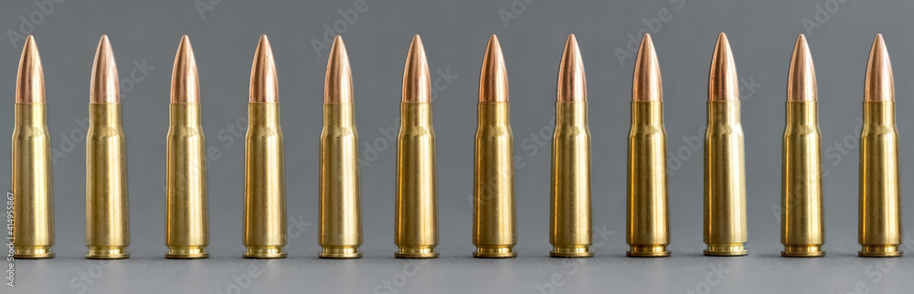 Bullets on gray background. Cartridges 7.62 caliber for Kalashnikov assault rifle closeup, horizontal banner Bullets on gray background. Cartridges 7.62 caliber for Kalashnikov assault rifle closeup, horizontal banner