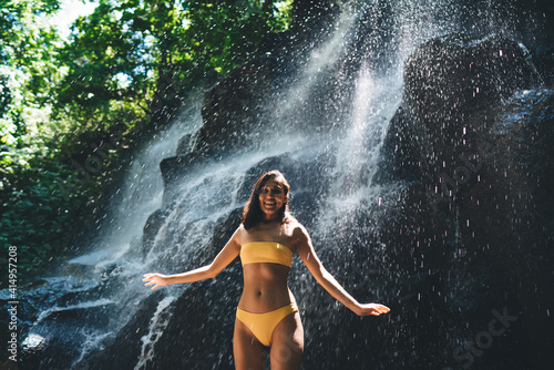 Woman standing in water stream under falls