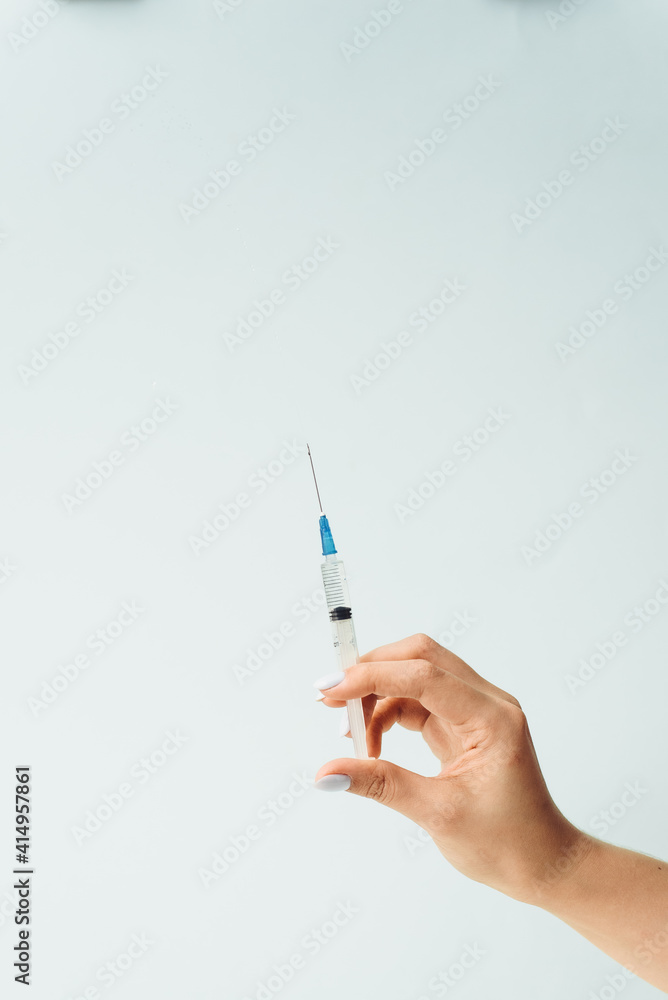 Doctor's hand holds a medical syringe on a blue background. The concept of medicine and medical care for the patient Doctor's hand holds a medical syringe on a blue background. The concept of medicine and medical care for the patient