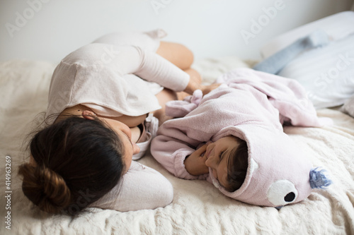 Pregnant woman with her daughter lying together on bed. © liderina
