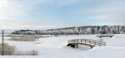 Wooden bridges and walking route. Snowy winter landscape at the lake shore.