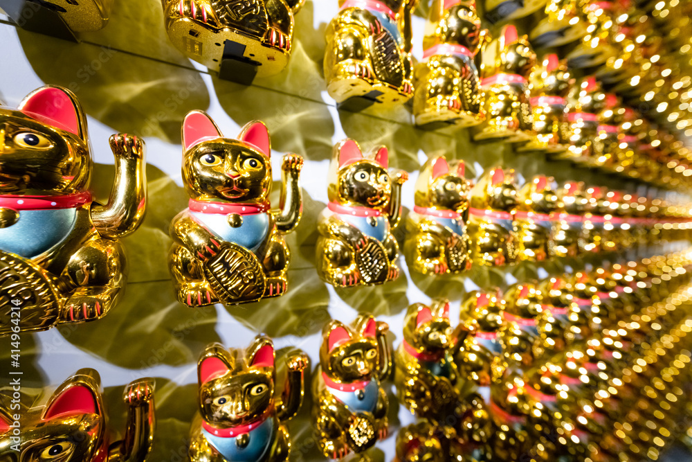 A wall with many Lucky Cats Maneki-Neko side view.