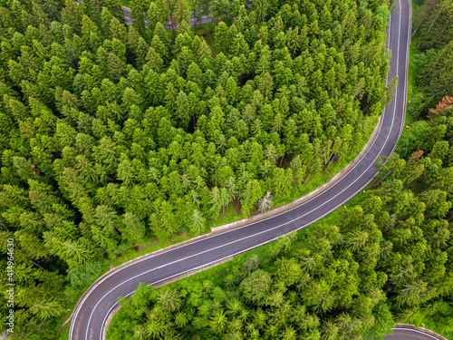Winding road through the forest, from high mountain pass, in summer time. Aerial view by drone. Romania