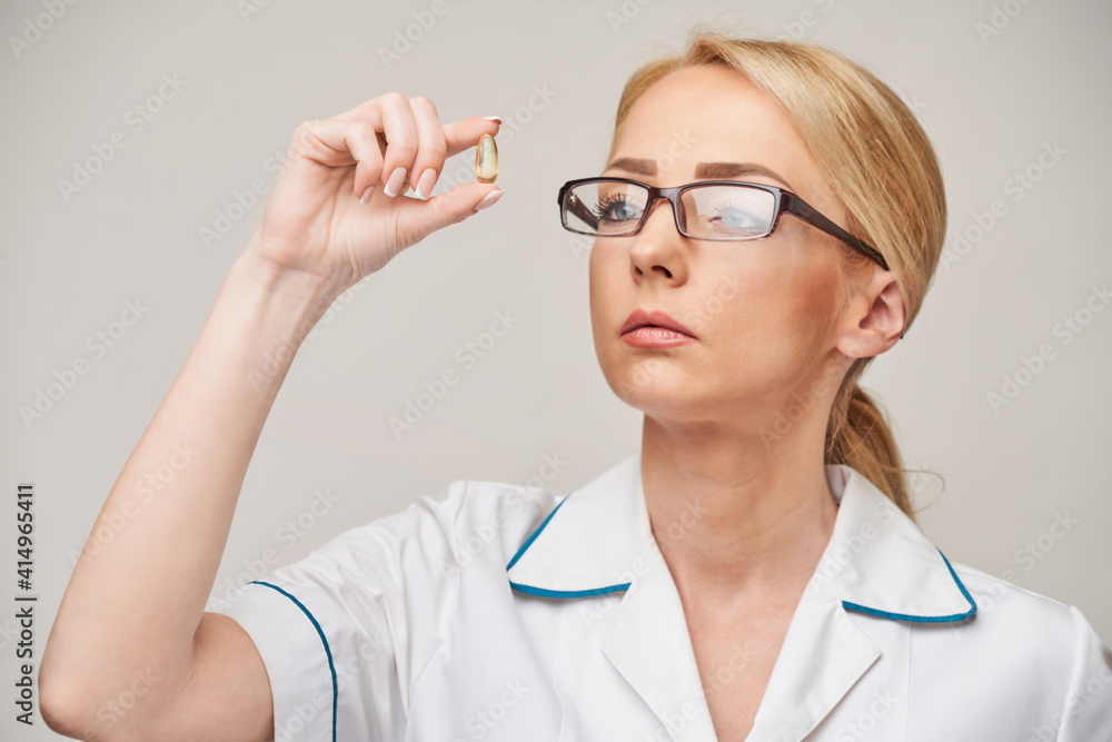 Health care and diet concept - doctor nutritionist or cardiologist holding fish oil in capsules for vitamin D and omega-3 fatty acids Health care and diet concept - doctor nutritionist or cardiologist holding fish oil in capsules for vitamin D and omega-3 fatty acids