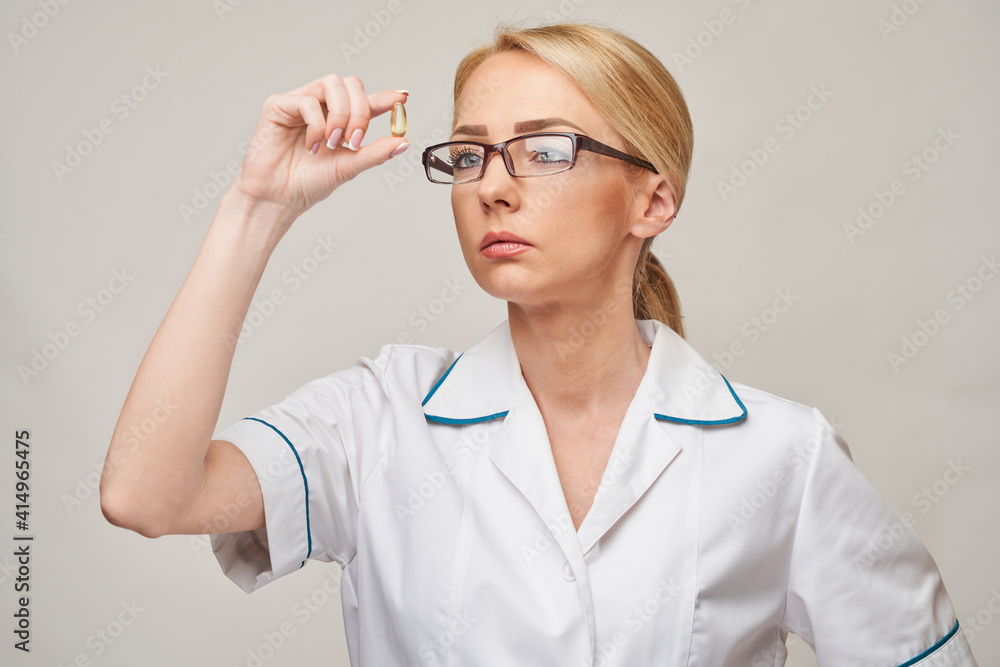 Health care and diet concept - doctor nutritionist or cardiologist holding fish oil in capsules for vitamin D and omega-3 fatty acids Health care and diet concept - doctor nutritionist or cardiologist holding fish oil in capsules for vitamin D and omega-3 fatty acids