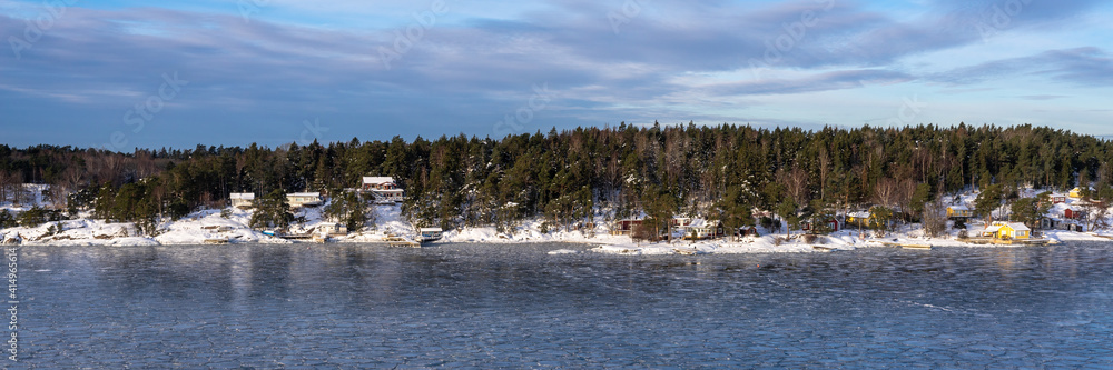 Beautiful view of the northern snow covered coast of the Baltic sea in winter day. Panorama of the shores of Scandinavia Sweden or Finland from cruise ship. Forestry islands on the horizon. Header.