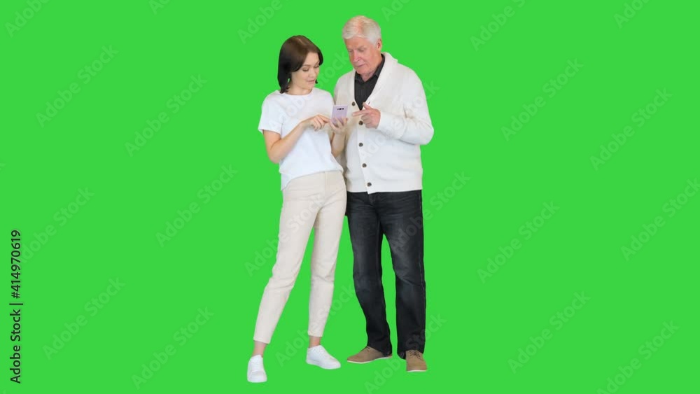 Daughter shows pictures on a mobile phone to her old father on a Green Screen, Chroma Key. Daughter shows pictures on a mobile phone to her old father on a Green Screen, Chroma Key.