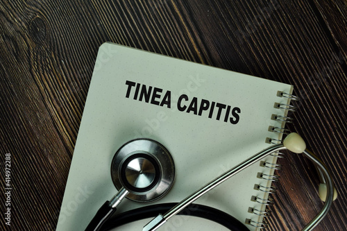 Tinea Capitis write on a book isolated on Wooden Table. Medical or Healthcare concept