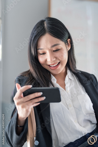 Asian businesswoman enjoying looking at the phone at the office. © amnaj