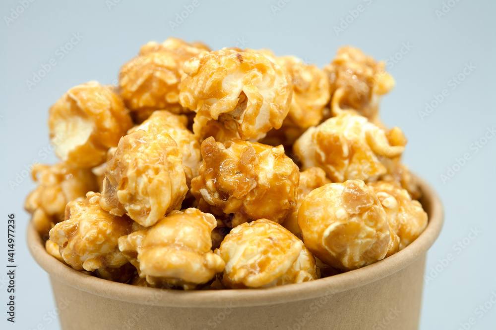 Caramelized popcorn in a paper cup. Close-up. Eco concept, craft paper cup. Macro photography. Caramelized popcorn in a paper cup. Close-up. Eco concept, craft paper cup. Macro photography.