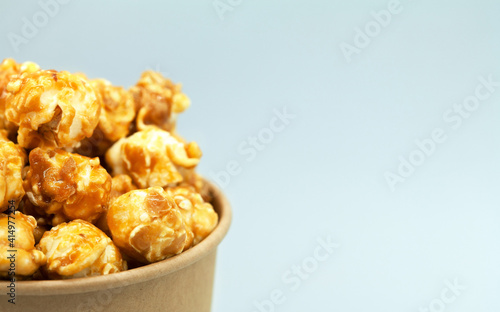 Caramelized popcorn in a paper cup. Close-up, macro photography. Cropped in half. Free space for text on the right.