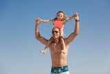 Un padre prende la figlia sulle spalle giocando simpaticamente con lei al mare in spiaggia