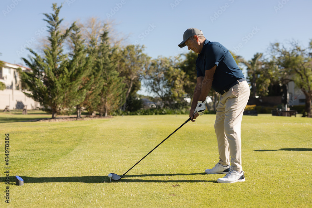 Caucasian senior man holding golf club preparing for shot on the green Caucasian senior man holding golf club preparing for shot on the green