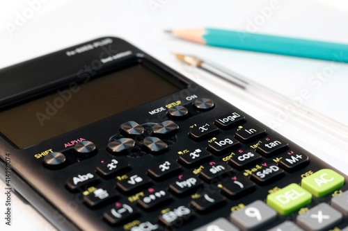 Scientific calculator, pen and pencil on a light background.