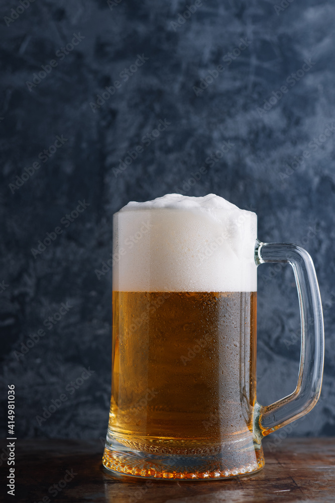 Pint mug of lager on the table, concrete dark background