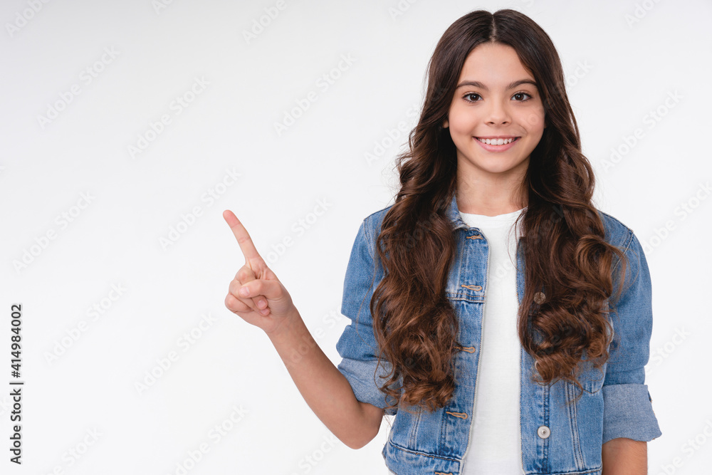 Smiling teen caucasian girl pointing at copy space in casual outfit isolated over white background Smiling teen caucasian girl pointing at copy space in casual outfit isolated over white background