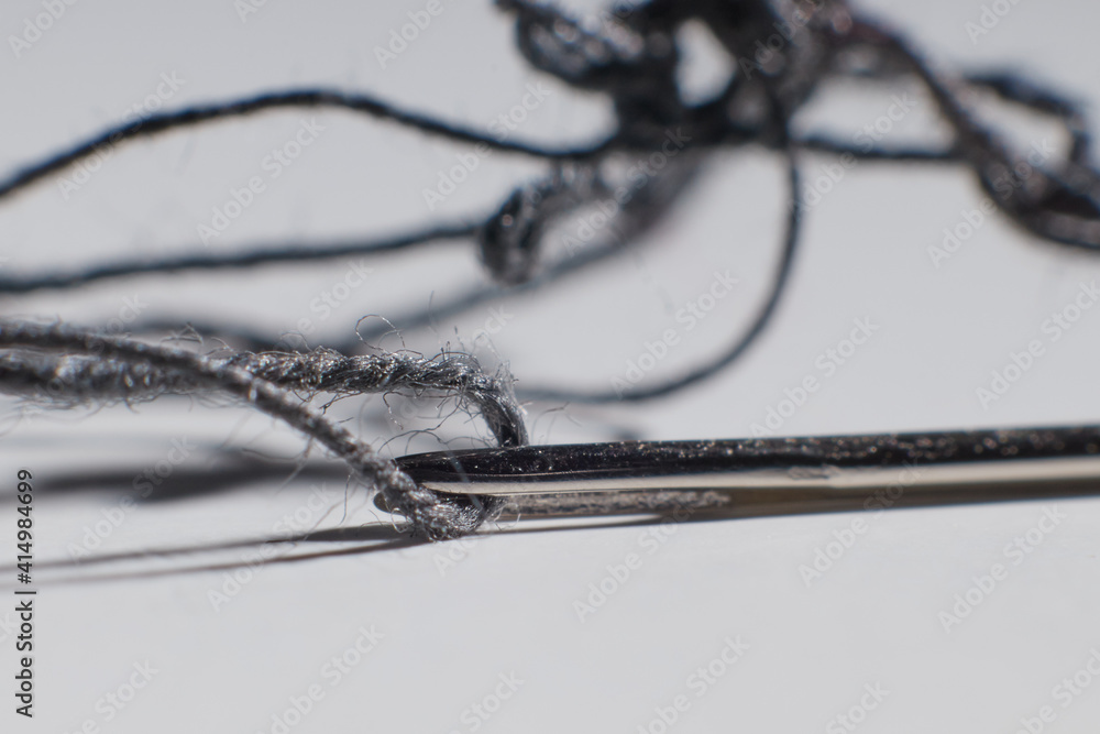 sewing needle with thread inside on the table macro photo blurred background
