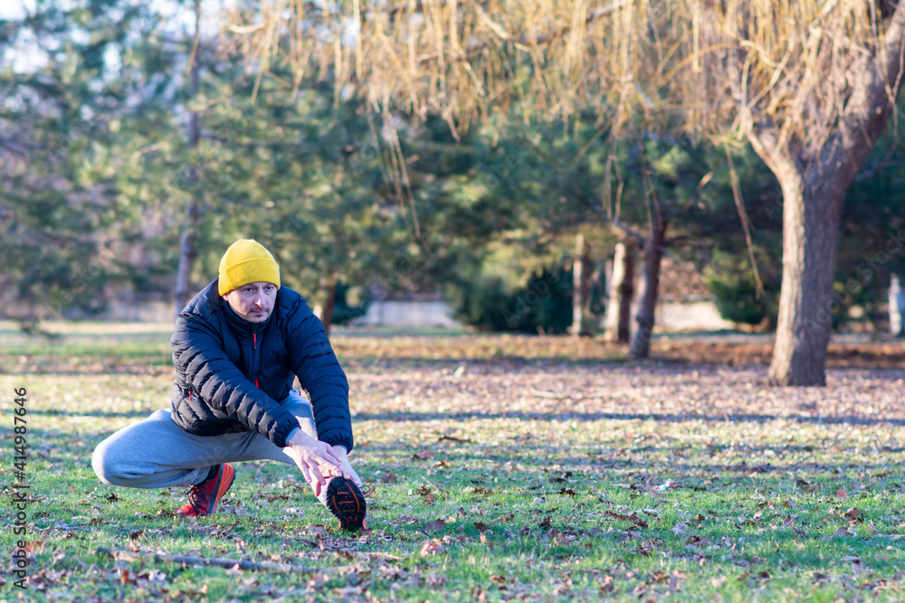 Adult man warming up in the park. man sitting pull toe feet stretching legs and knee before running at outdoor street health park, healthy exercise before workout concept