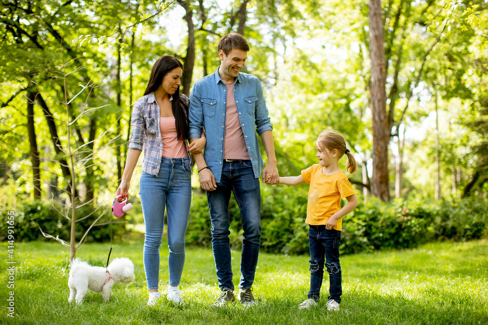 Obraz premium Happy family with cute bichon dog in the park