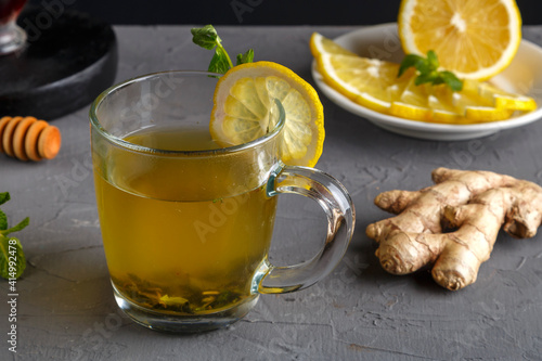 immune ginger drink with honey mint and lemon in a glass cup next to ingredients.