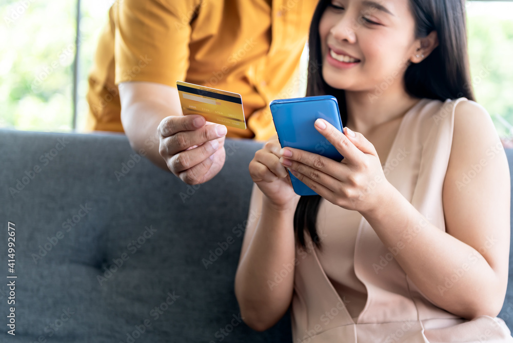 Blurred soft images of Asian attractive wife Using mobile phones and looking at mock up credit card, which her husband holds for shopping online, to business and shopping online concept. Blurred soft images of Asian attractive wife Using mobile phones and looking at mock up credit card, which her husband holds for shopping online, to business and shopping online concept.