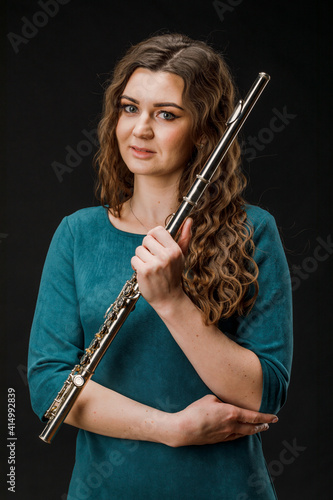 Portrait of a woman playing a transverse flute  isolated on a black background.