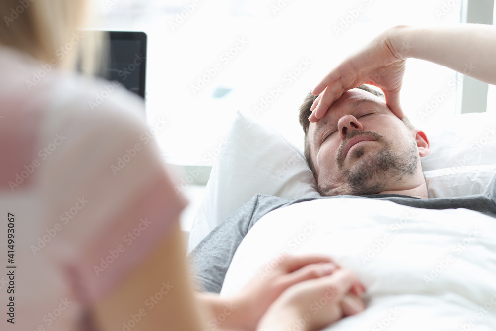 Woman visitor holding hand of sick man in hospital room Woman visitor holding hand of sick man in hospital room