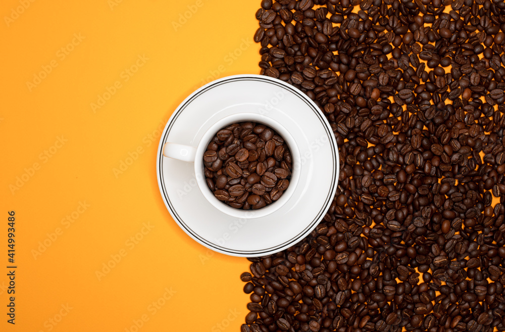 Naklejka premium Top view of coffee cup with many coffee beans on the one side and on the other side yellow background for copy space