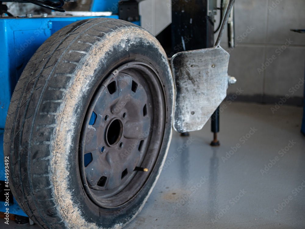 MECHANIC IN HIS WORKSHOP FIXING CAR WHEEL IN MACHINE MECHANIC IN HIS WORKSHOP FIXING CAR WHEEL IN MACHINE
