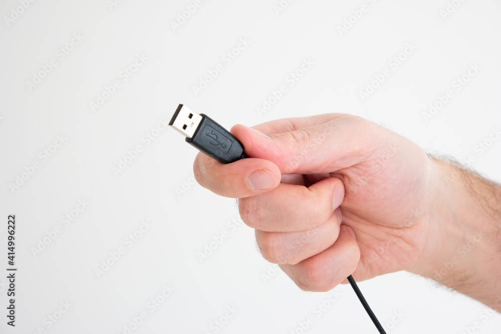 USB cable ad connector held in hand by Caucasian male hand isolated on white background USB cable ad connector held in hand by Caucasian male hand isolated on white background