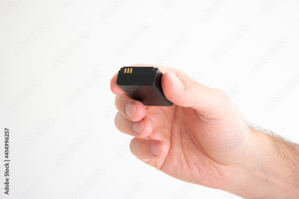 Black square format rechargeable battery held in hand by Caucasian male hand isolated on white Black square format rechargeable battery held in hand by Caucasian male hand isolated on white