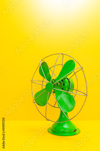 Old green electric fan on yellow background
