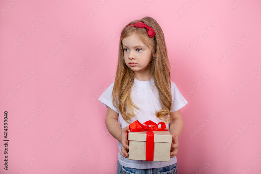 Little girl with a gift in a box standing on a pink background Little girl with a gift in a box standing on a pink background