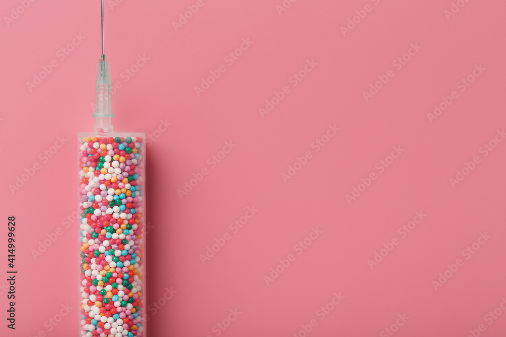 Obraz premium Syringe with colorful balloons on a pink background with free space.