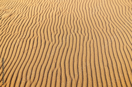 Close-up texture of the rippled surface of the sand and dunes, top view. Desert background