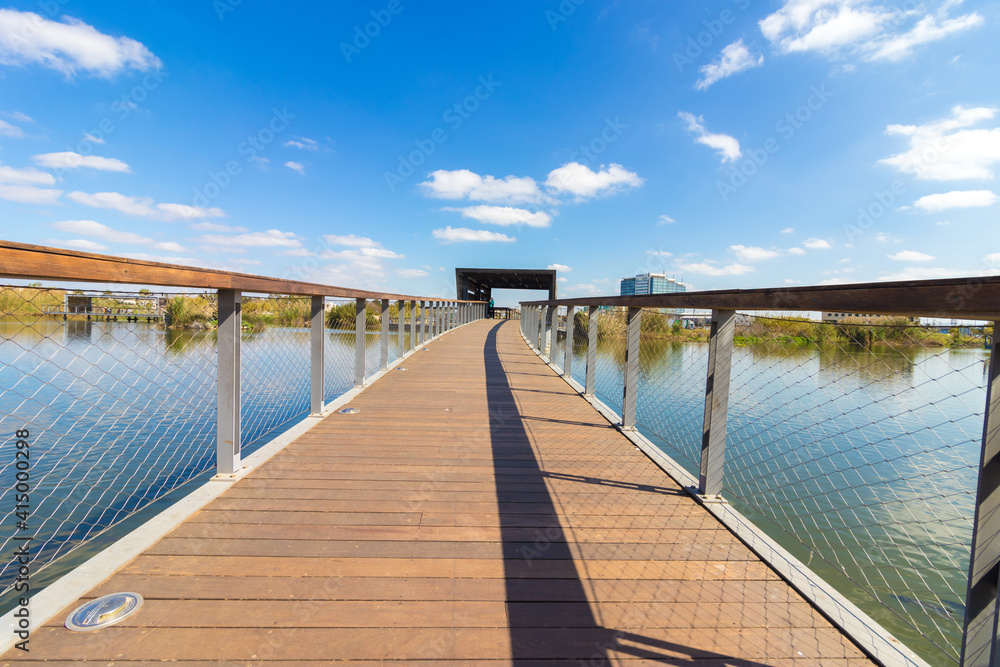 A wooden bridge over an artificial ecological lake, in a park in Hod Hasharon