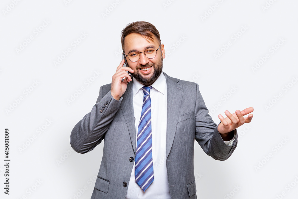 businessman wearing glasses wearing business gray suit smiling and talking on cellphone isolated. light background businessman wearing glasses wearing business gray suit smiling and talking on cellphone isolated. light background