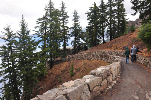 Three people walking on a trail leading towards Crater Lake National Park