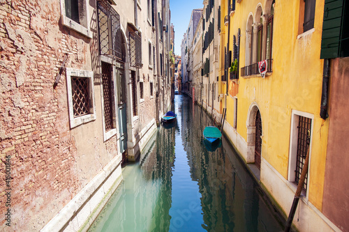 Boats rest in a small canal among colorful facades, Venice, Italy