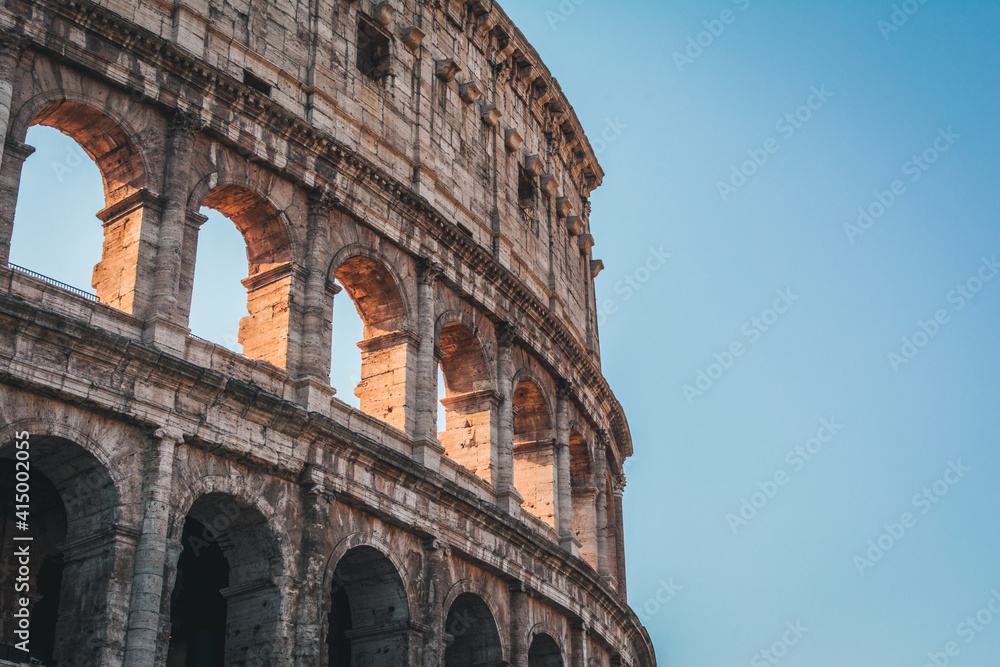 Coliseum (Colosseum), Rome, Italy. Ancient Roman Coliseum is famous landmark, top tourist attraction of Rome. Scenic view of Coliseum with trees and blue sky. Sunny old Coliseum close-up in summer.