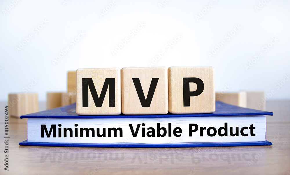 Obraz premium MVP, minimum viable product symbol. Wooden cubes on book with words MVP, minimum viable product. Beautiful white background. Business and MVP, minimum viable product concept, copy space.