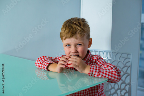 Boy sits at the table and eats a delicious bar.