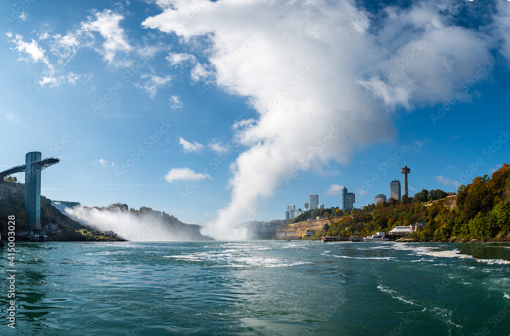 A low angle view of the Niagara falls from the Niagara river with a huge cloud forming from the Canadian falls