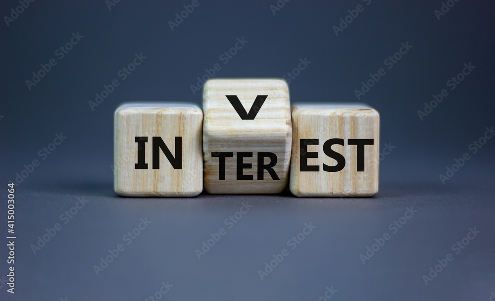 Invest or interest symbol. Turned a wooden cube and changed the word 'invest' to 'interest'. Beautiful grey background, copy space. Business and invest or interest concept. Invest or interest symbol. Turned a wooden cube and changed the word 'invest' to 'interest'. Beautiful grey background, copy space. Business and invest or interest concept.