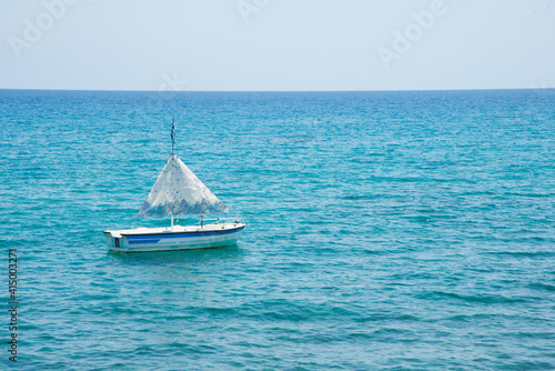 A small boat with no people and blue waters on a sunny day. Close to Lindos, Rhodes, Greece