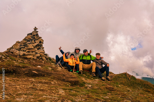 A group of tourists are sitting smiling on top of the mountains of the Montenegrin ridge, Mount Rebra is one of the peaks of the Carpathian mountains. photo